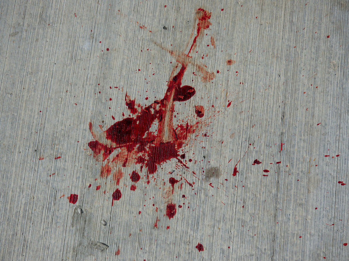 Rote Farbkleckse auf grauem Untergrund, stellvertretend für das vergossene Blut bei der Schlachtung von Tieren in der Tierindustrie.