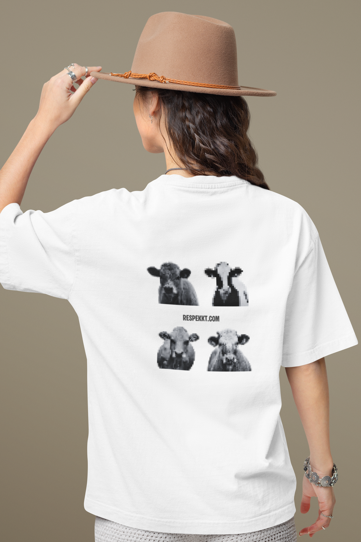Frau mit braunem Hut und weißem Oversized T-Shirt auf dessen Rücken vier Kühe im Profil in grauen Pixeln abgedruckt sind, sowie die Webadresse dieser Website: "respekkt.com"